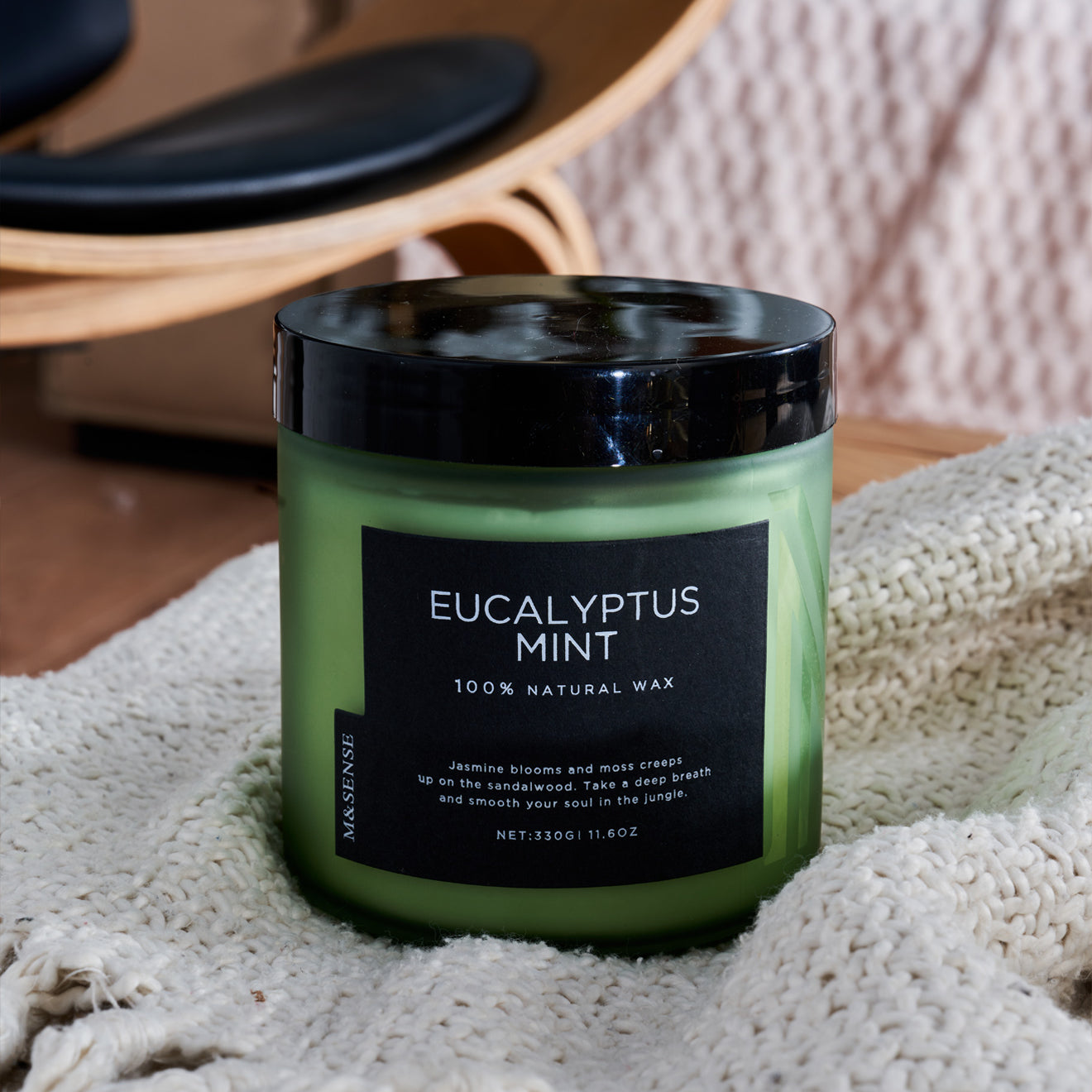Eucalyptus mint scented candle in a green frosted jar, adding a fresh aroma to a cozy living room setting with a sofa.