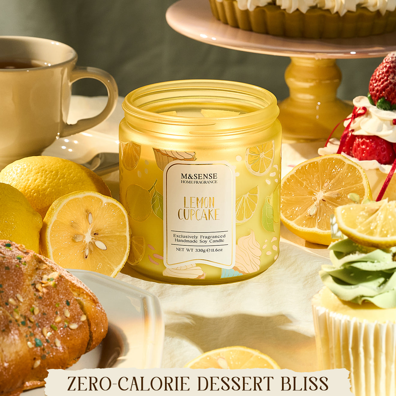 Jar of M&N Sense Lemon Cupcake candle with lemons, cupcakes, and a cake in the background.
