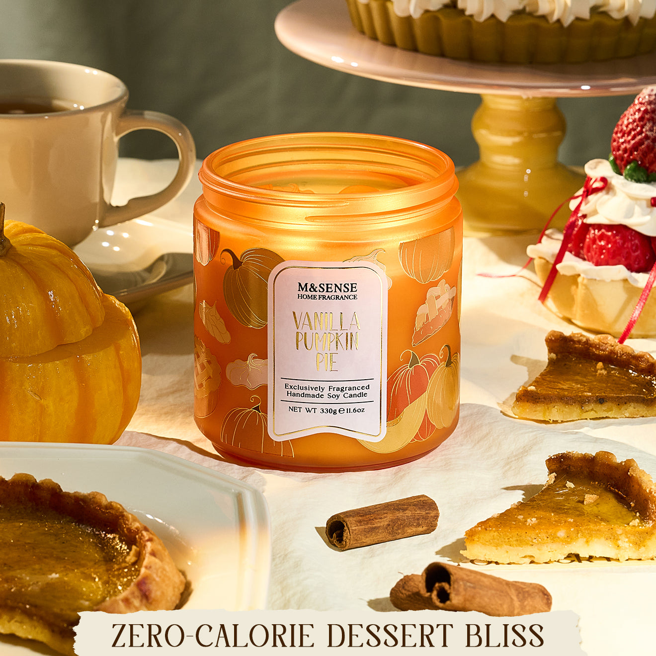 Orange candle labeled 'Vanilla Pumpkin Pie' on a table with desserts and a cup.