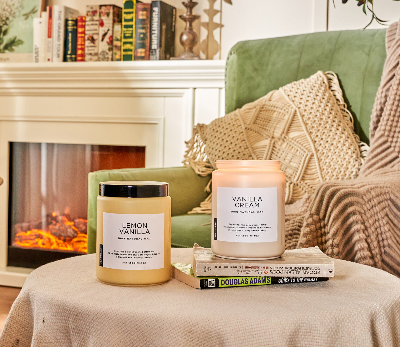 Two scented candles on a draped round coffee table, in a living room with sofa and bookshelf.