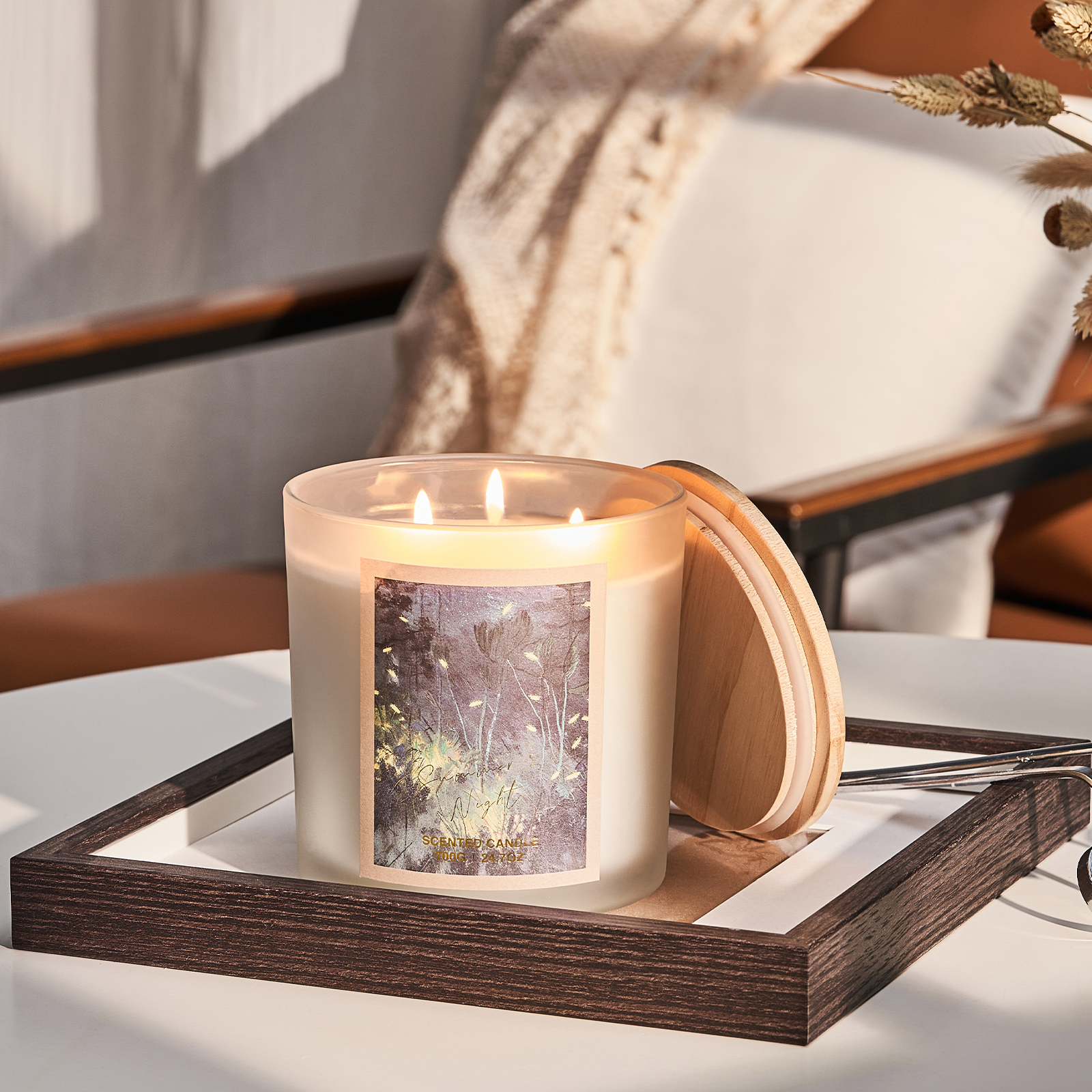 Candle with wooden lid on a tray, surrounded by natural elements