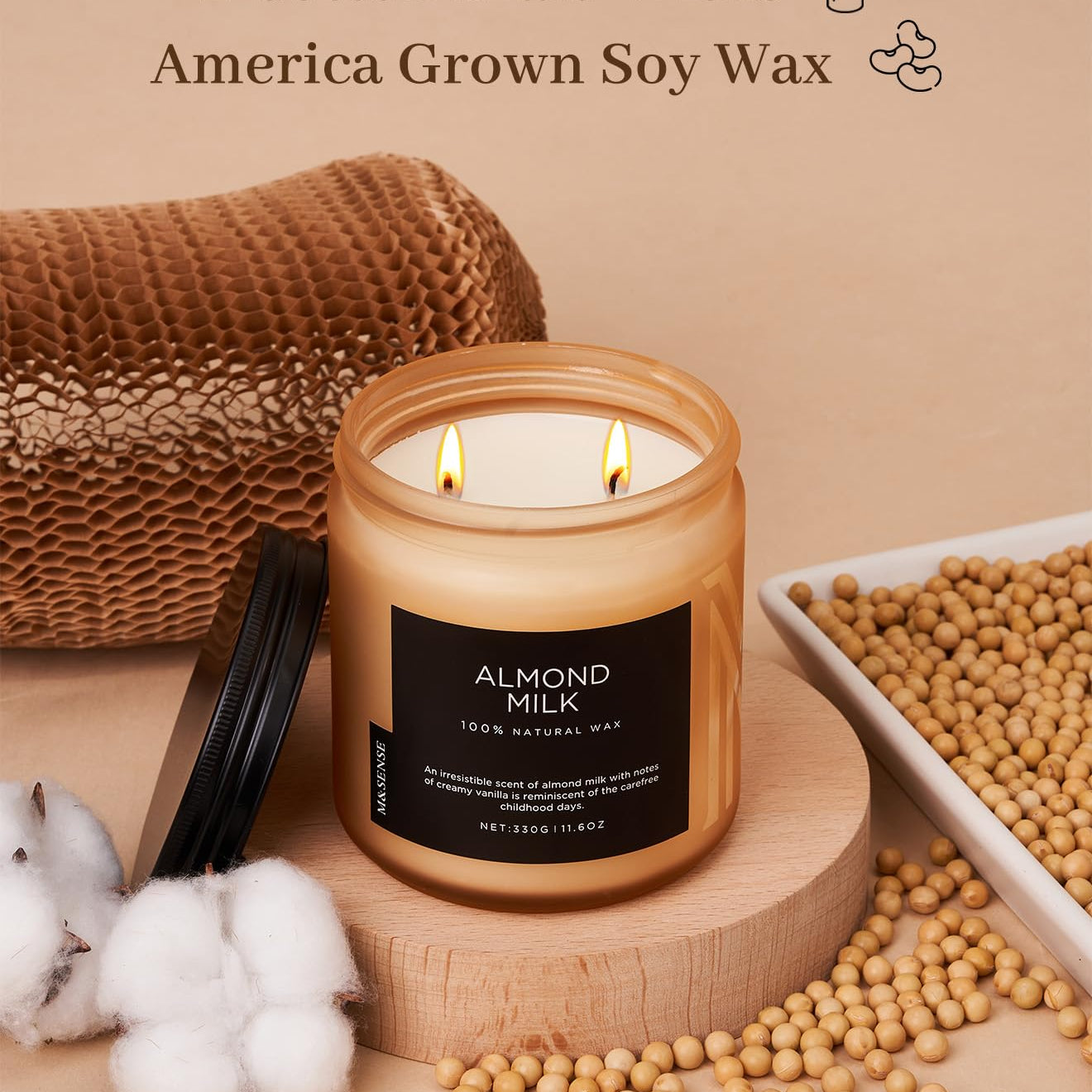Candle with 'Almond Milk' label, surrounded by soybeans and cotton, on a beige background.