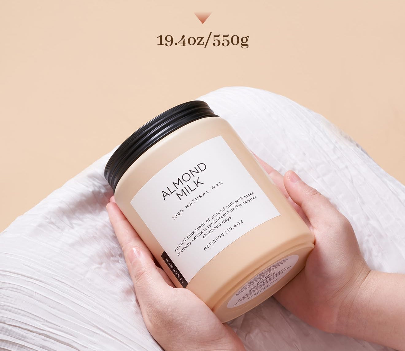 Candle labeled 'Almond Milk' held by a hand with text indicating burn time and weight on a beige background