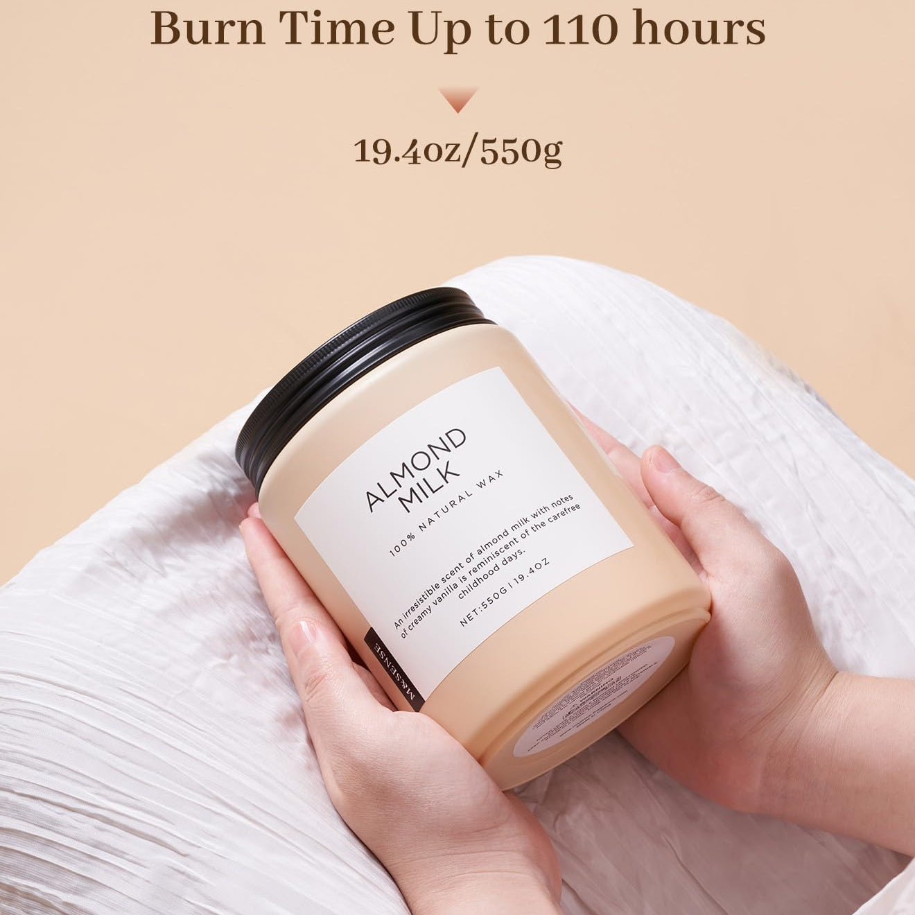 Candle labeled 'Almond Milk' held by a hand with text indicating burn time and weight on a beige background