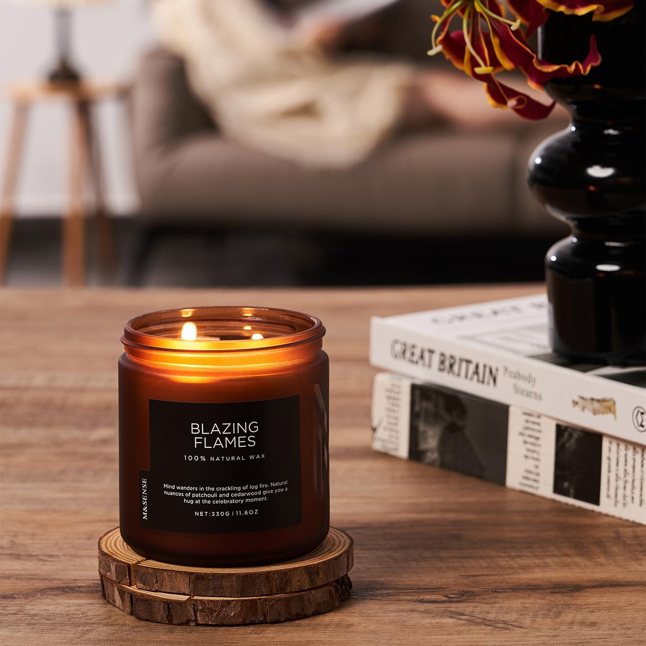 Candle labeled 'Blazing Flames' on a wooden coaster with a blurred background of a cozy living room.