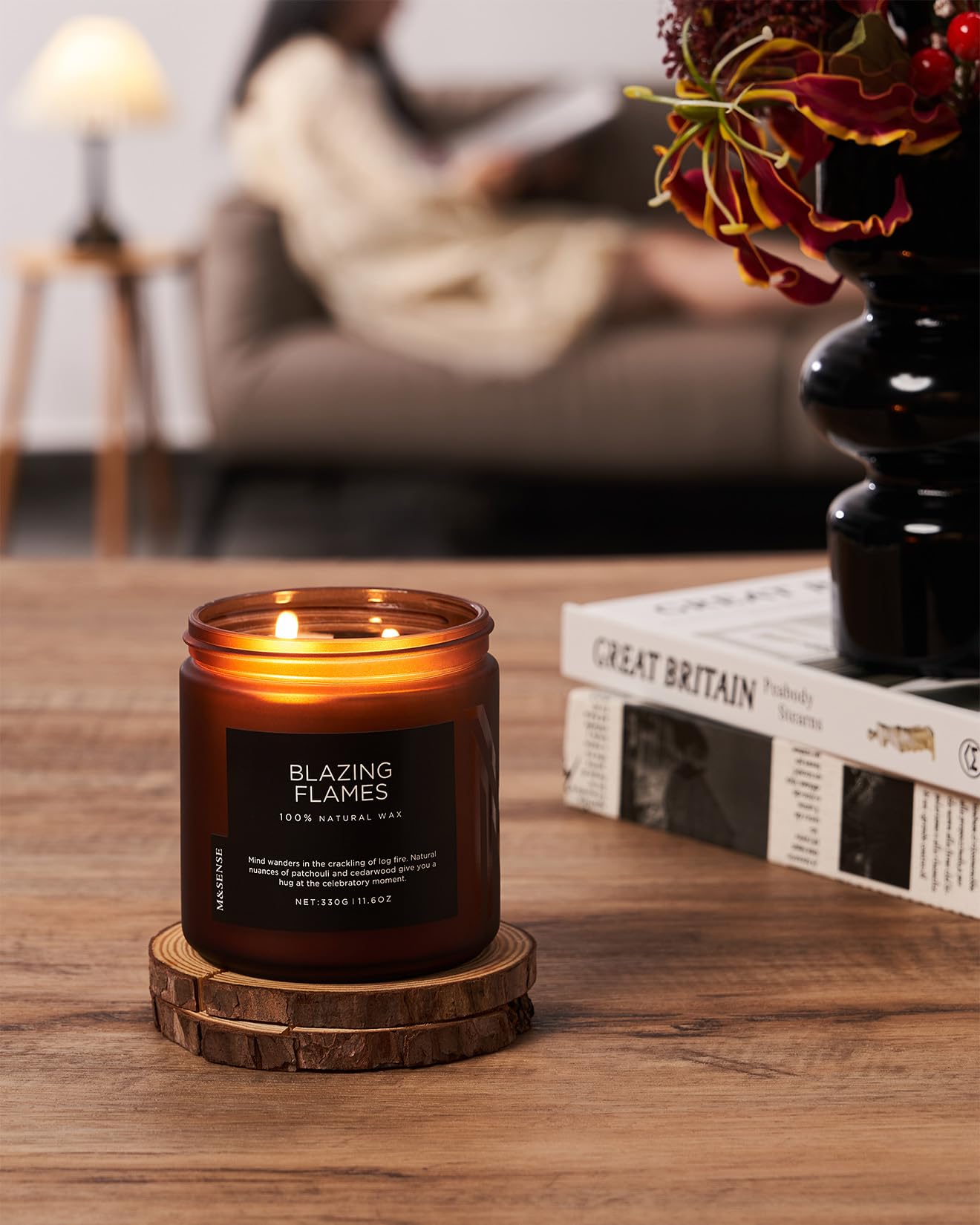 Candle labeled 'Blazing Flames' on a wooden coaster with a blurred background of a cozy living room.