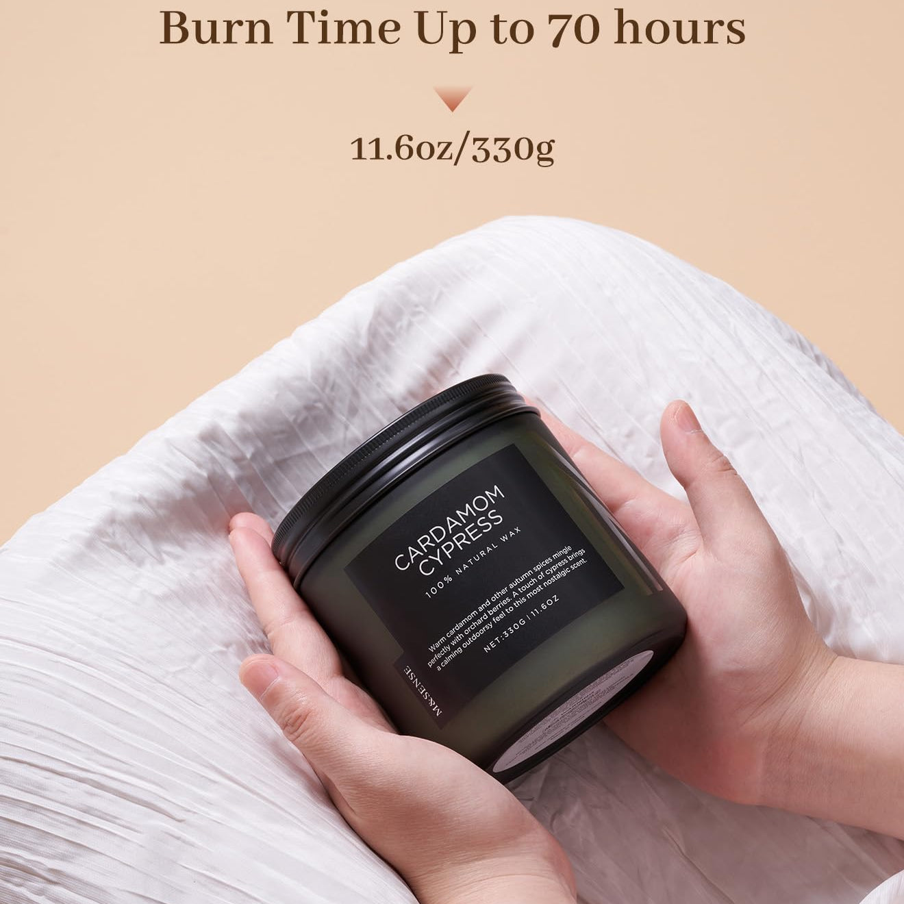 Hand holding a candle labeled 'Cinnamon Cypress' with text about burn time and weight on a beige background.