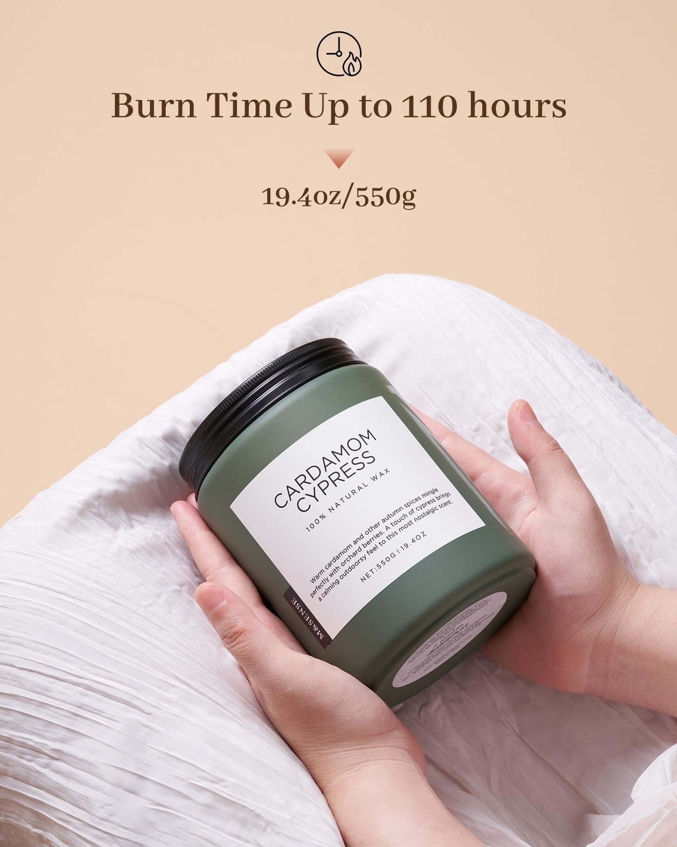 Hand holding a green candle labeled 'Cardamom Cypress' with text about burn time and weight on a beige background.