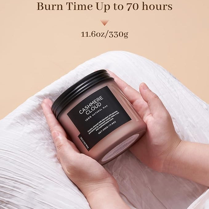 Candle with a label held by hands against a beige background, featuring text about burn time and weight.