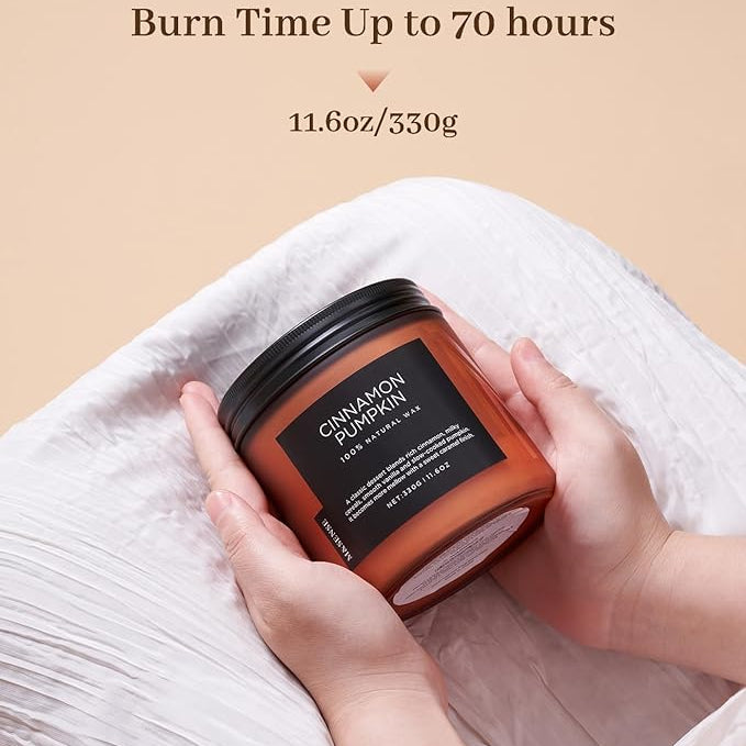 Candle jar labeled 'Cinnamon Pumpkin' held by hands with text indicating burn time and weight.
