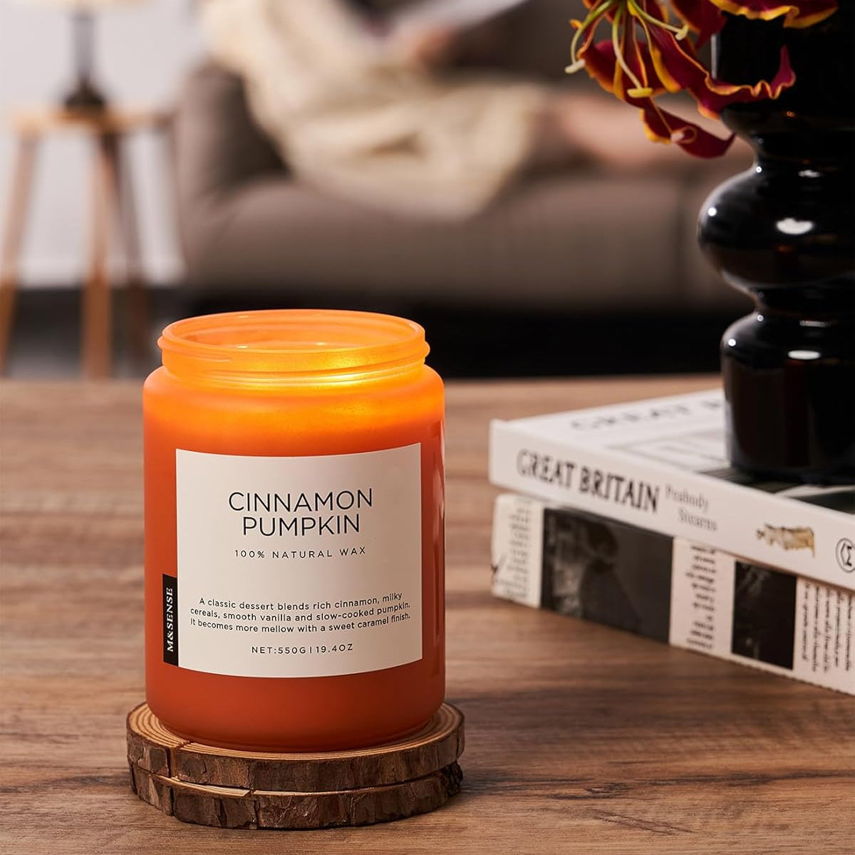 Cinnamon pumpkin candle on a wooden coaster with a blurred background of a living room.