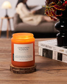 Cinnamon pumpkin candle on a wooden coaster with a blurred background of a living room.