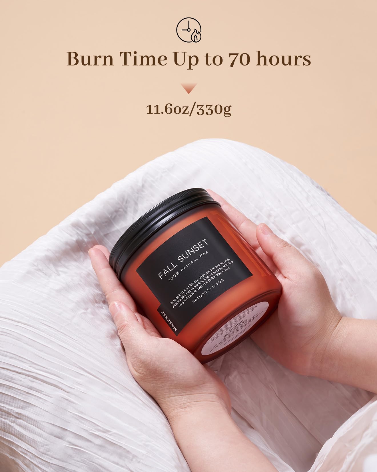 Candle labeled 'Fall Sunset' held by a hand with a beige background