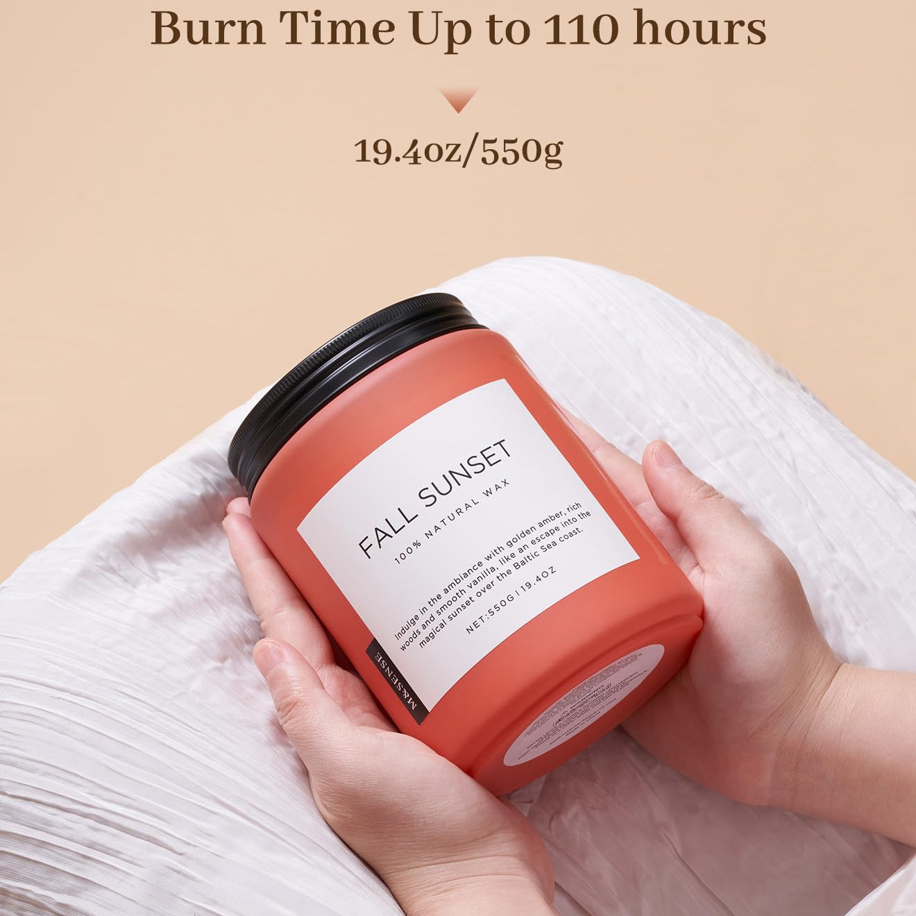 Candle labeled 'Fall Sunset' held by a person with a beige background