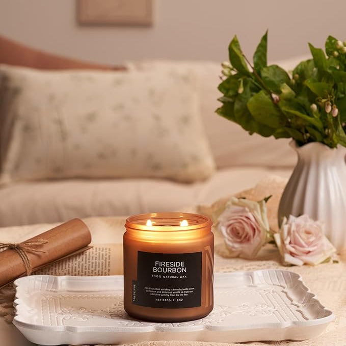 Candle labeled 'Fireside Bourbon' on a tray with flowers and a vase in a cozy living room setting.
