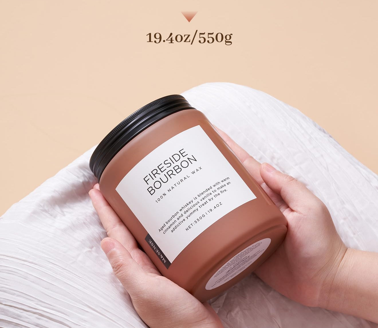 Candle labeled 'Fireside Bourbon' held by a hand with a beige background