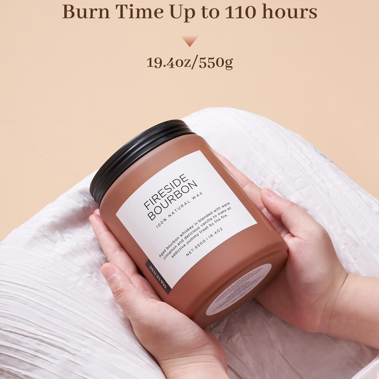 Candle labeled 'Fireside Bourbon' held by a hand with a beige background