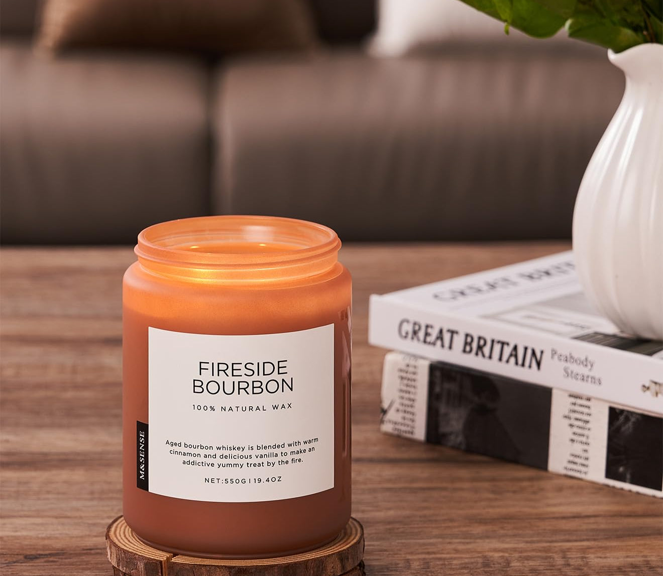 Fireside Bourbon candle on a wooden coaster with a couch and books in the background