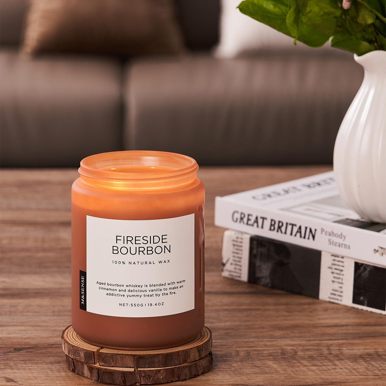 Fireside Bourbon candle on a wooden coaster with a couch and books in the background