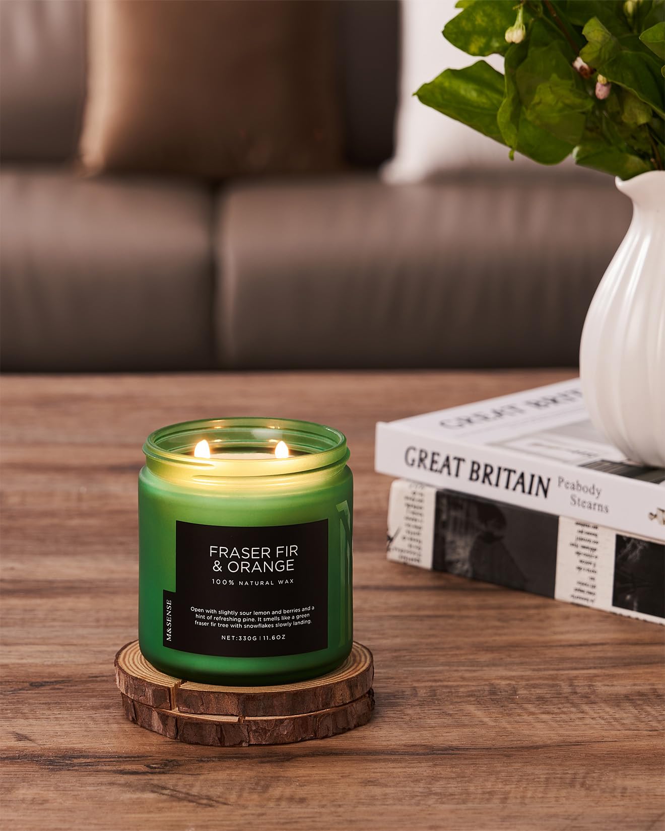 Green candle with a label on a wooden coaster in a living room setting.