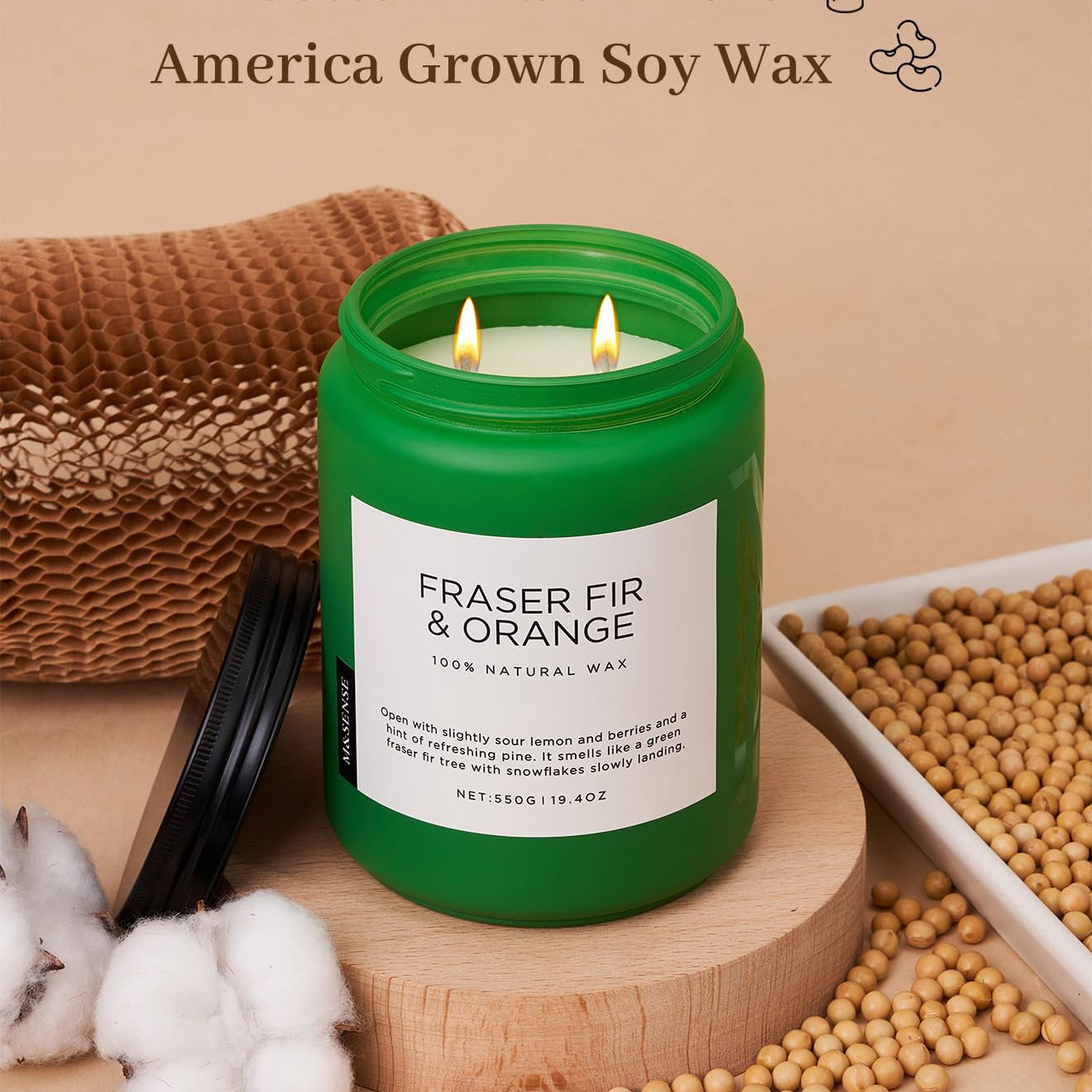 Green candle labeled 'Fraser Fir & Orange' with cotton braid wicks and soy wax on a wooden surface.