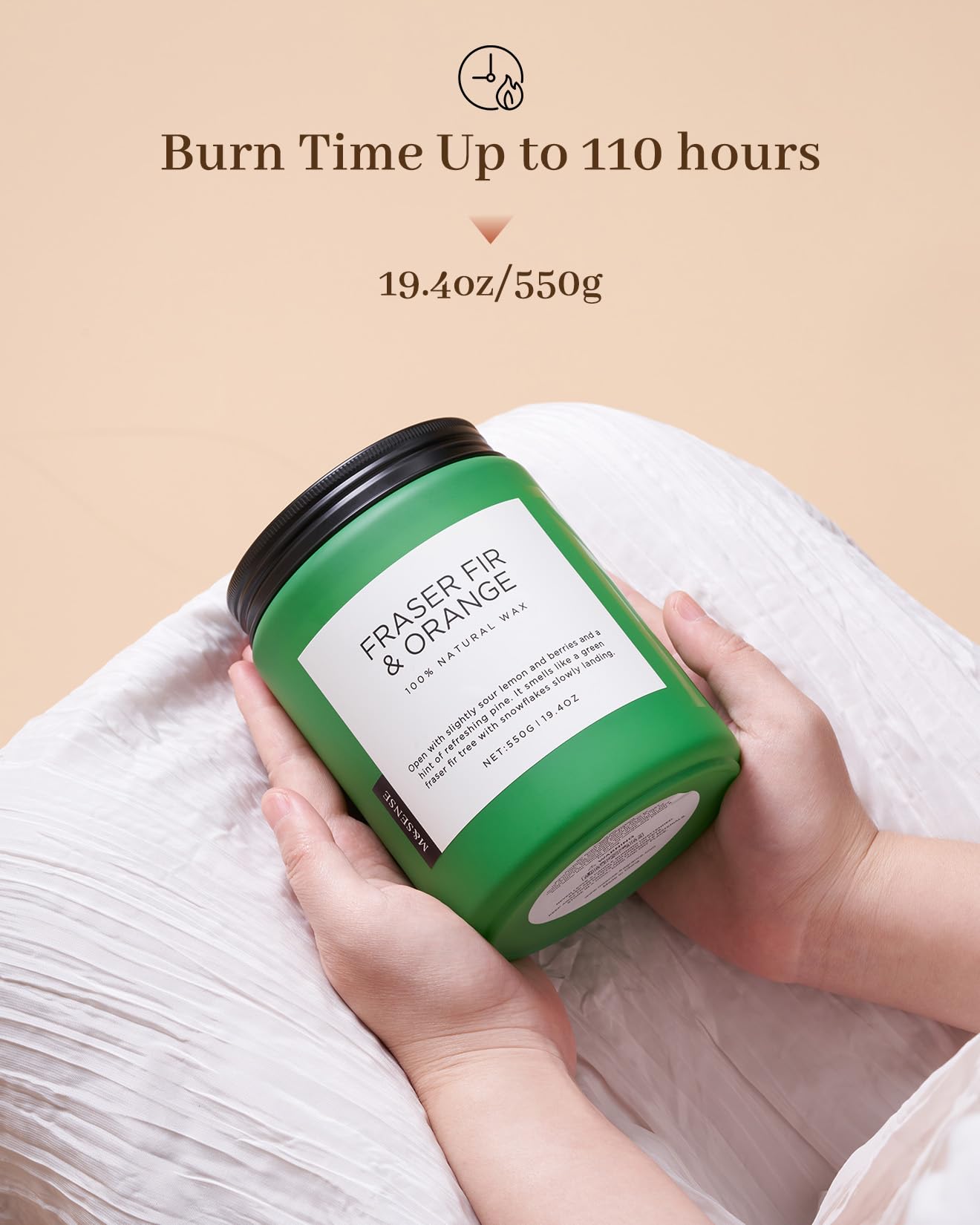 Green candle labeled 'Eraser Fir & Orange' held by a hand on a beige background with text about burn time.