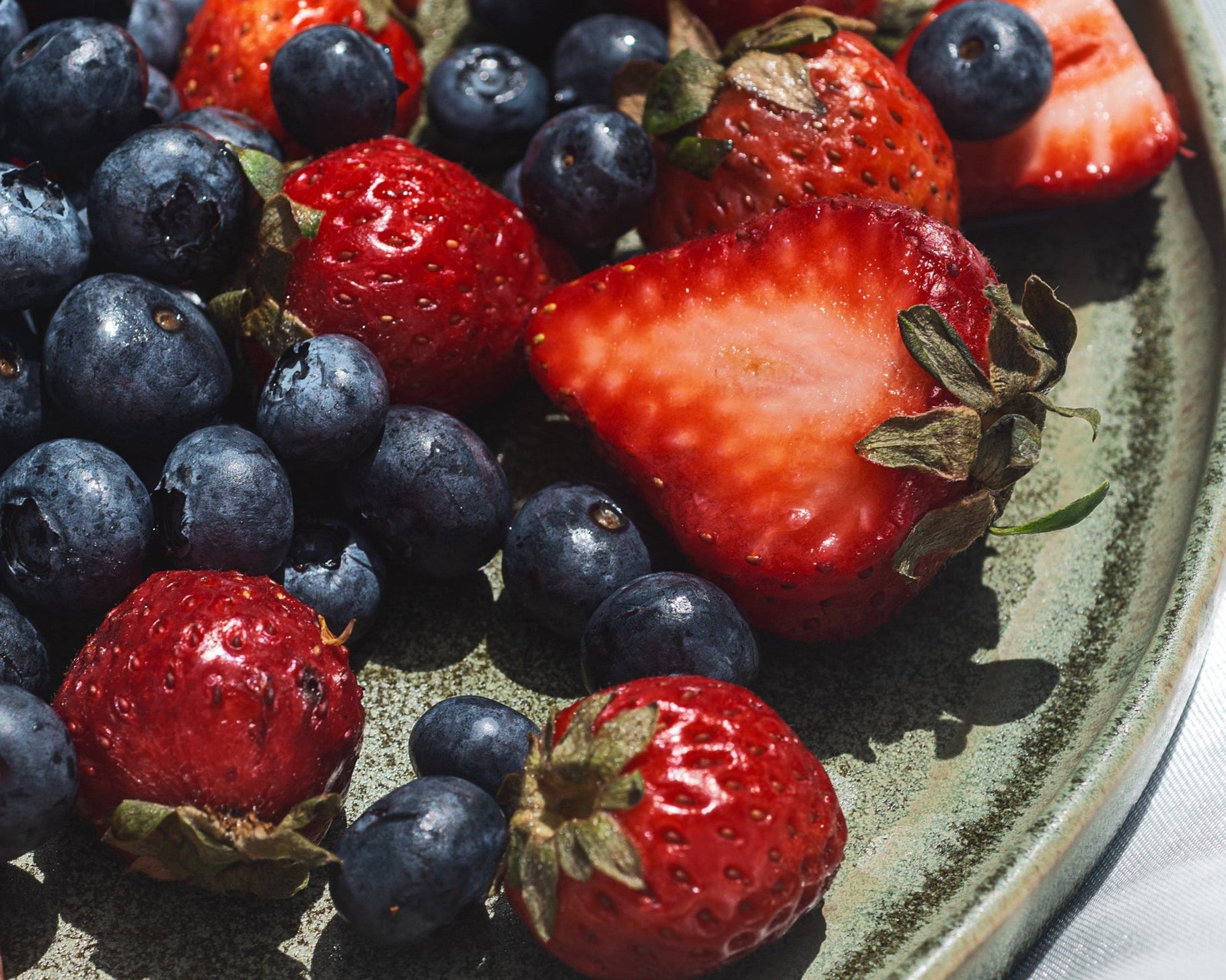 Plate with blueberries and strawberries on a white surface