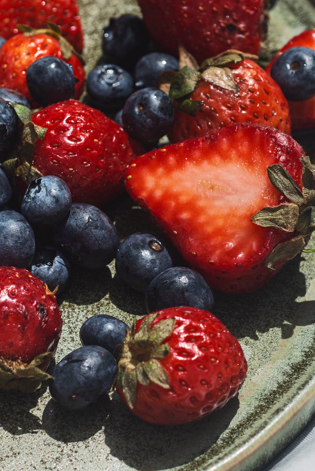 Plate with blueberries and strawberries on a white surface