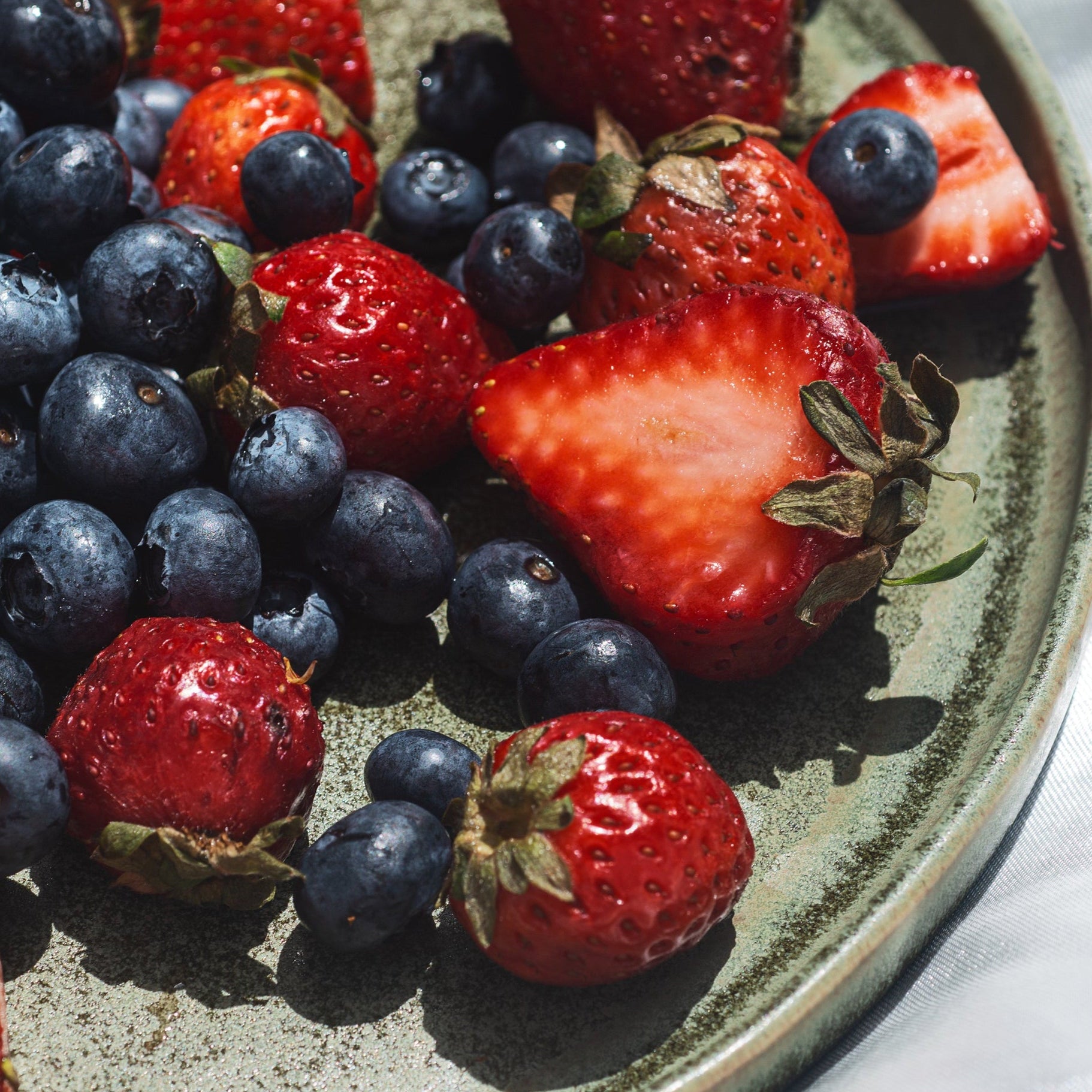 Plate with blueberries and strawberries on a white surface