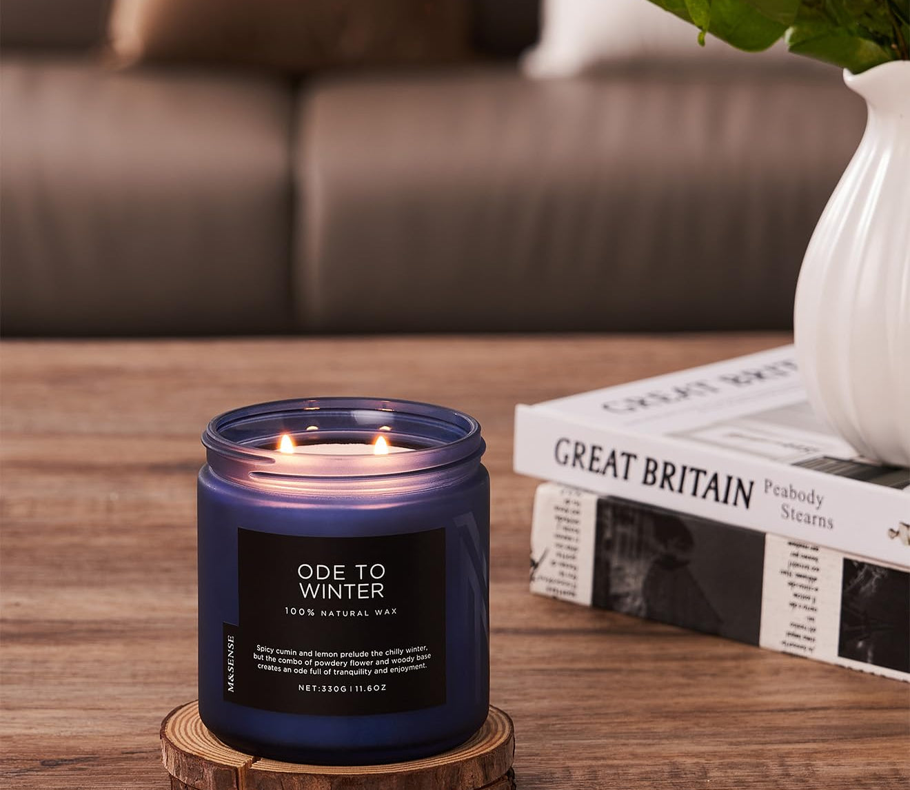 Candle labeled 'Ode to Winter' on a wooden coaster with a blurred background