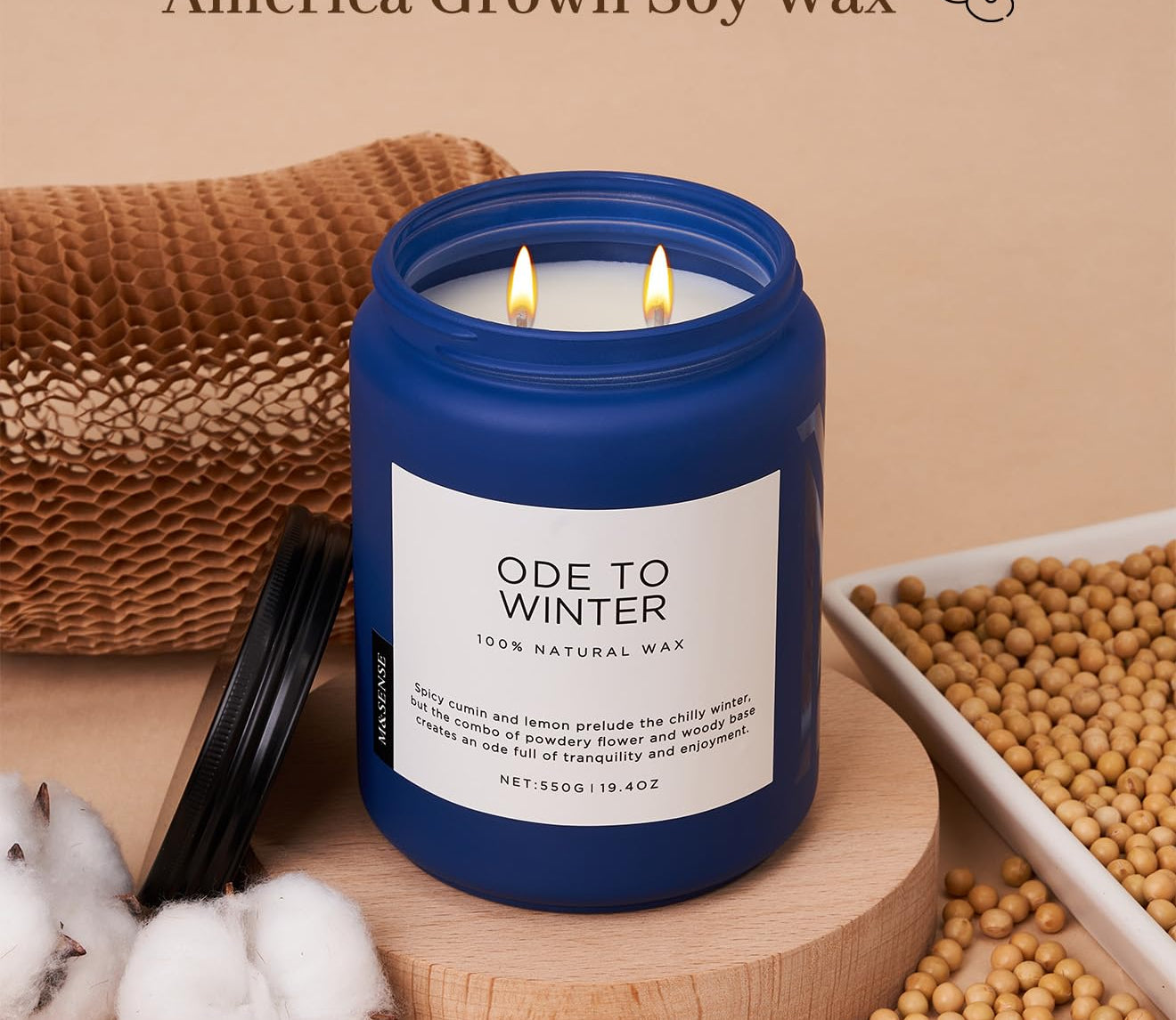 Candle with blue lid and white label on a wooden stand, surrounded by cotton and soybeans, with text about wicks and wax.