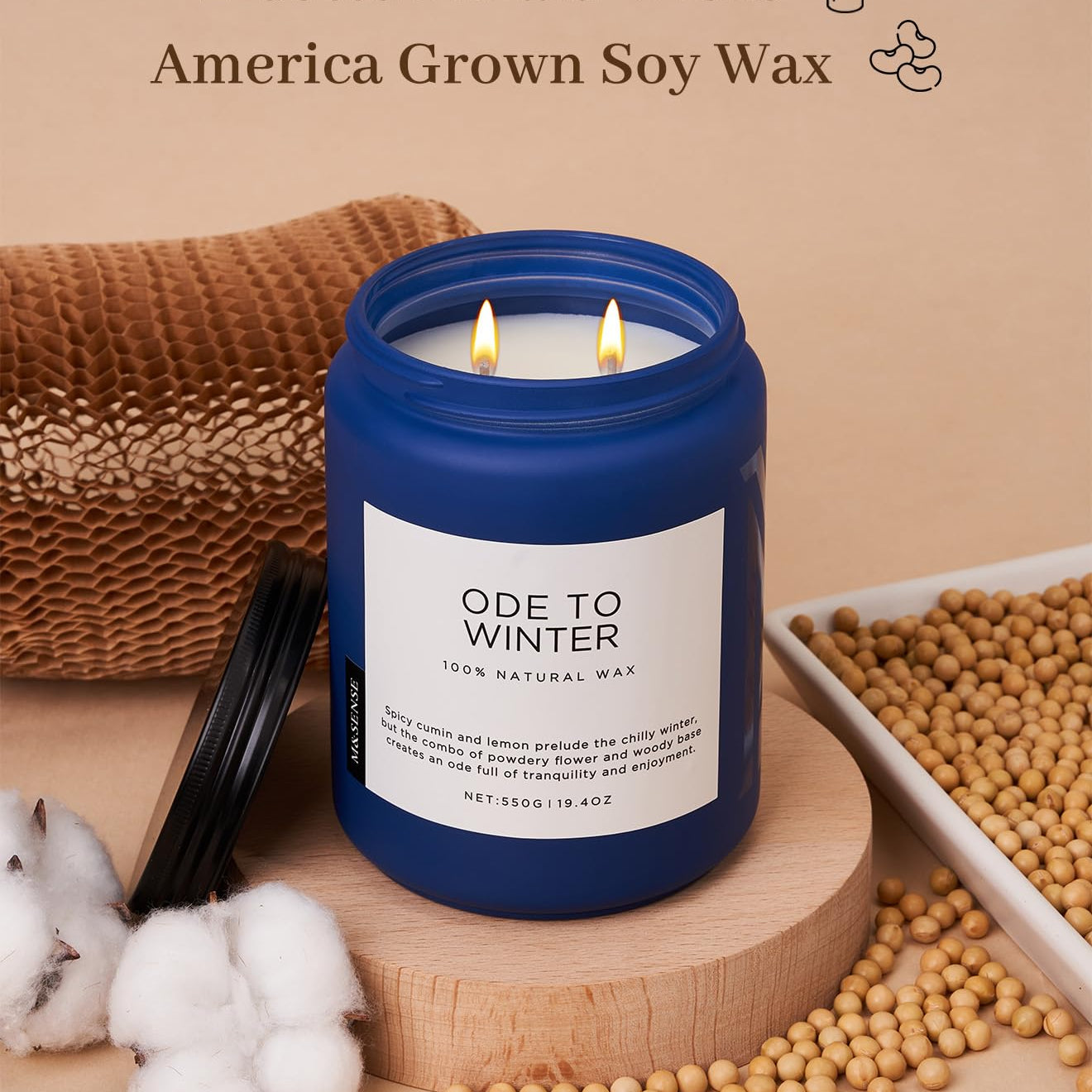 Candle with blue lid and white label on a wooden stand, surrounded by cotton and soybeans, with text about wicks and wax.