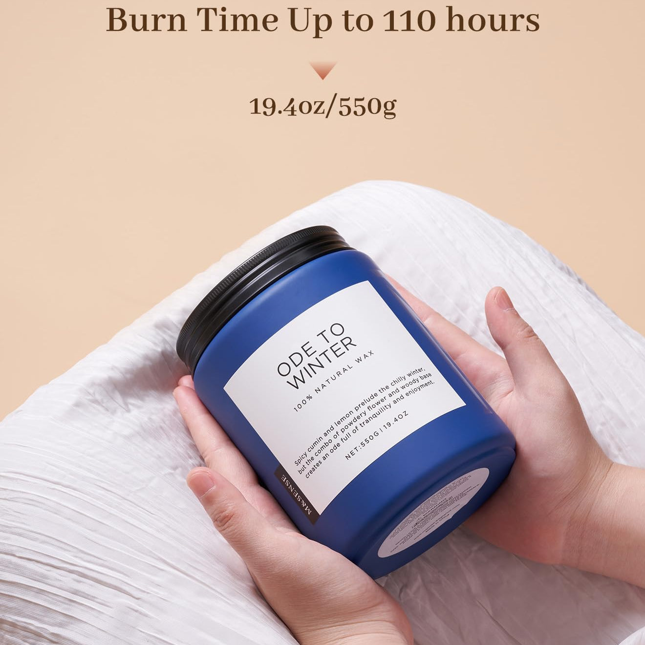 Blue candle labeled 'Ode to Winter' held by a hand with beige background