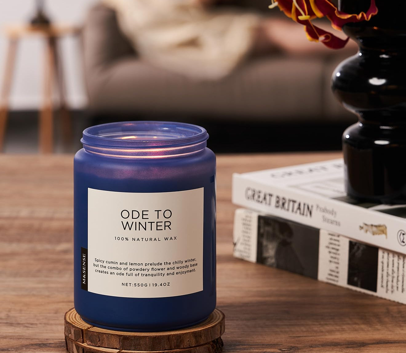 Blue candle labeled 'Ode to Winter' on a wooden table with a blurred background