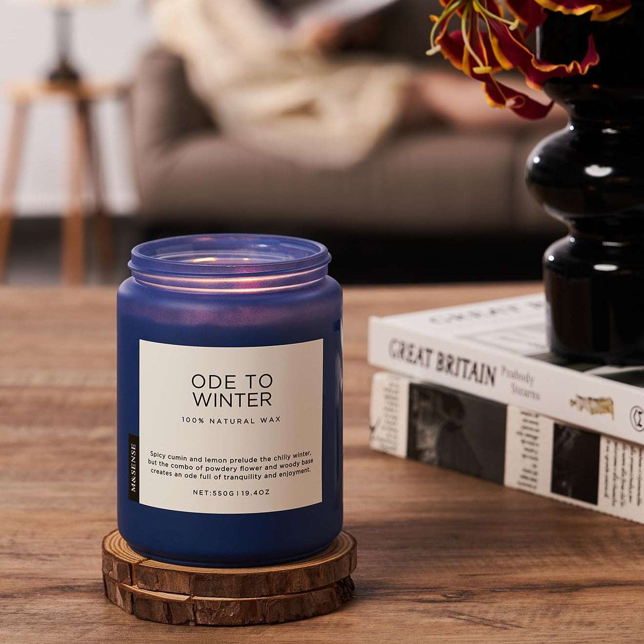 Blue candle labeled 'Ode to Winter' on a wooden table with a blurred background
