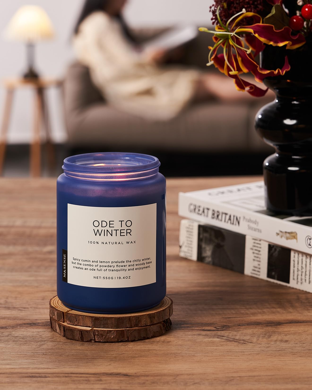 Blue candle labeled 'Ode to Winter' on a wooden table with a blurred background