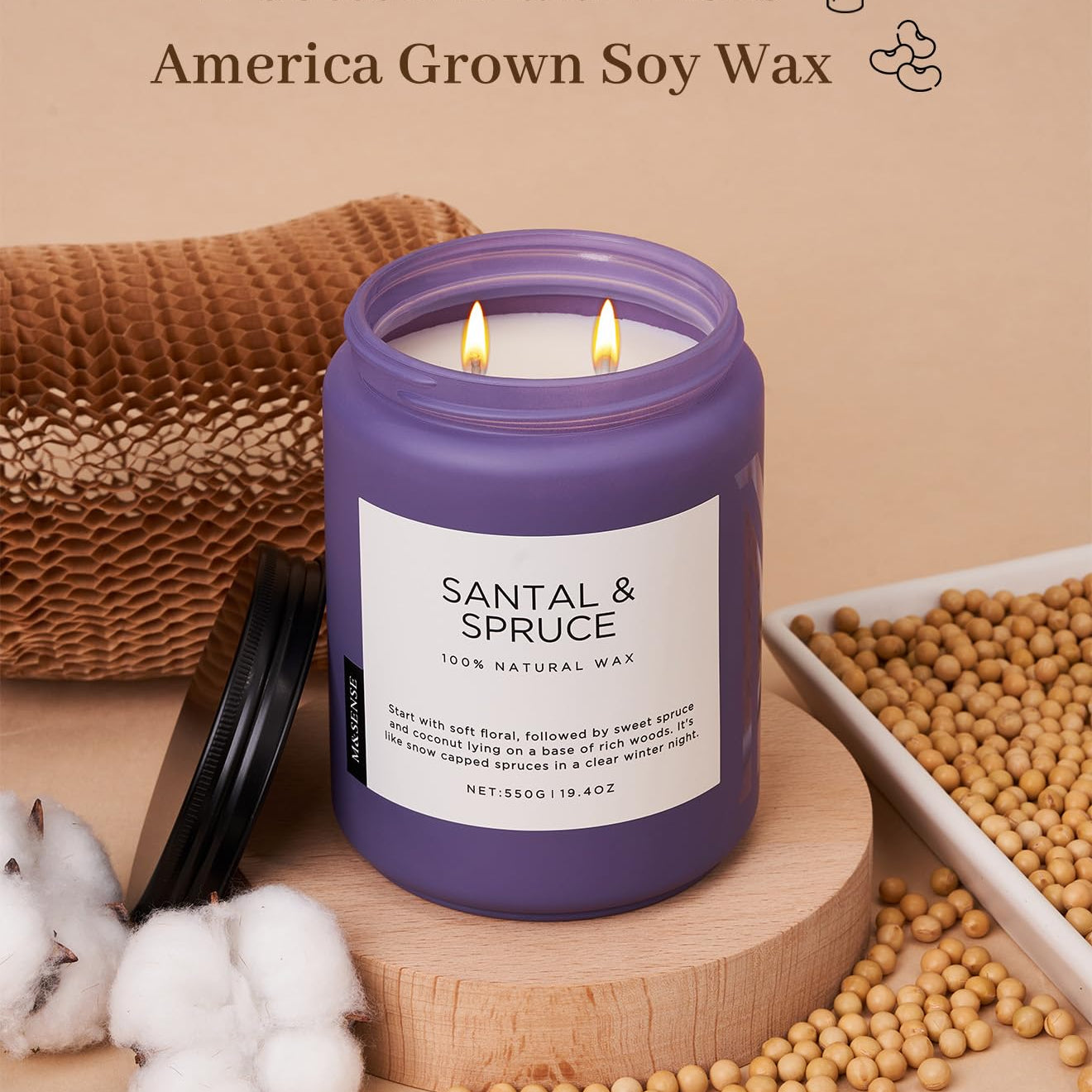 Purple candle labeled 'Santal & Spruce' with cotton braid wicks and soy wax on a wooden surface.