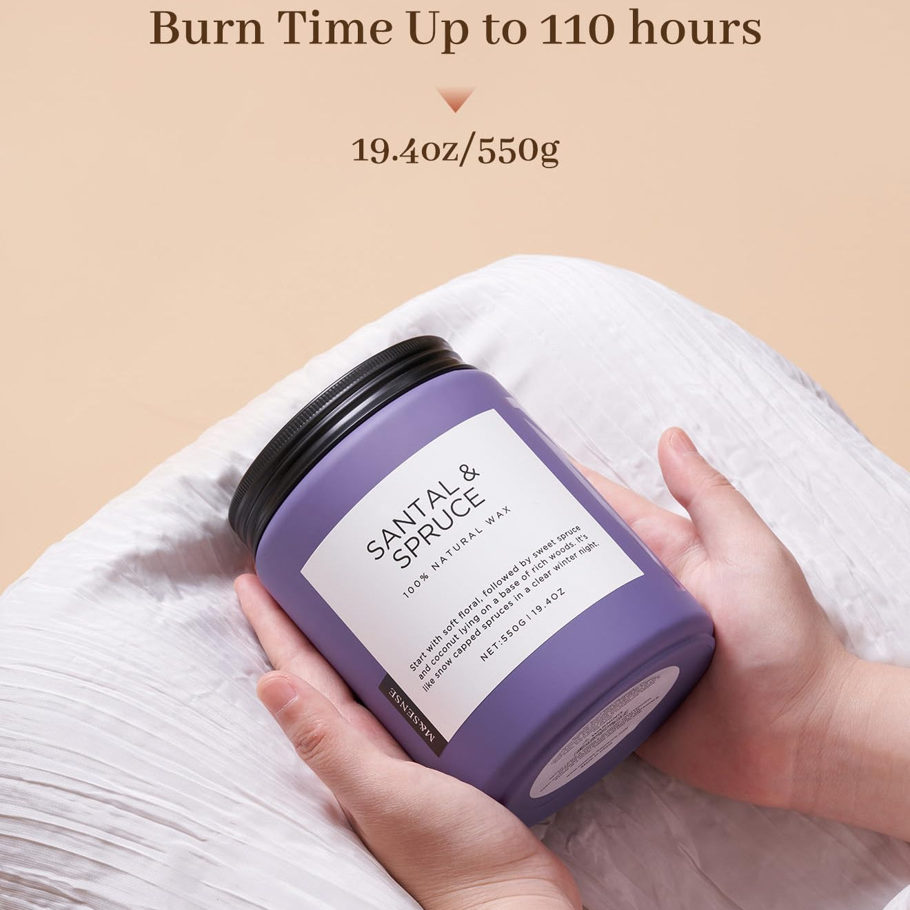 Hand holding a purple candle labeled 'Santal & Spruce' with text about burn time and weight on a beige background.