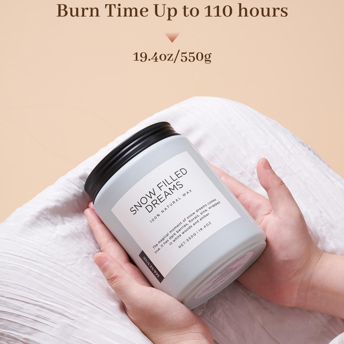 Candle labeled 'Snow Filled Dreams' held by a hand with beige background