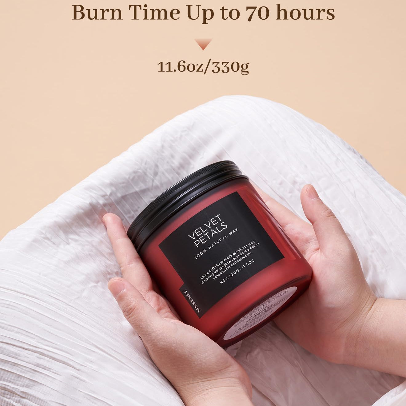 Red candle with black lid held by hands on a beige background, featuring text about burn time and weight.
