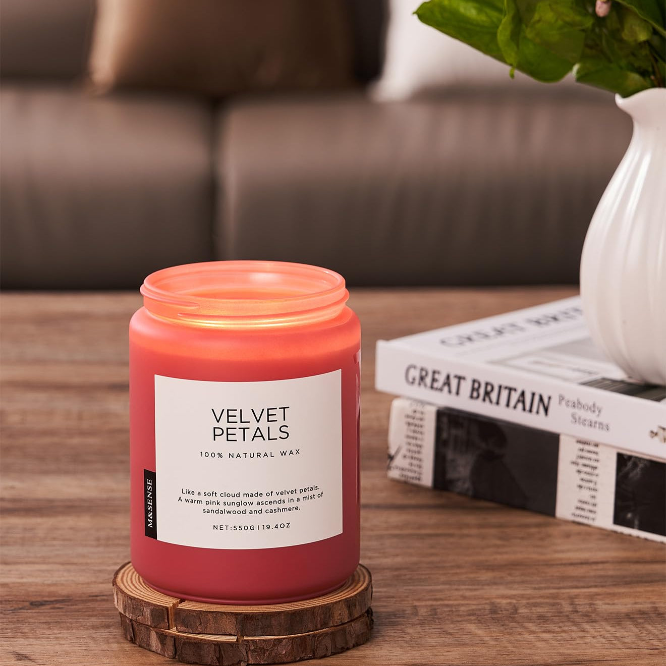 Pink candle labeled 'Velvet Petals' on a wooden coaster with a blurred background
