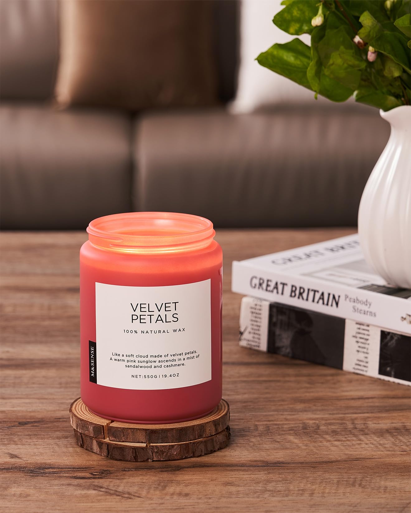 Pink candle labeled 'Velvet Petals' on a wooden coaster with a blurred background