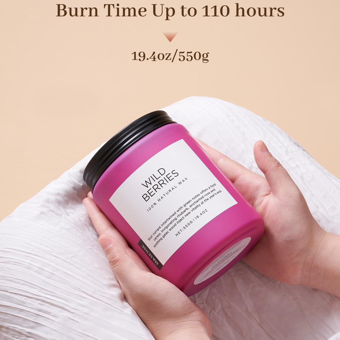 Pink candle labeled 'Wild Berries' held by a hand with beige background