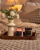 Bedroom decor with cherry blossom and roast coffee scented candles on wooden tray beside vase