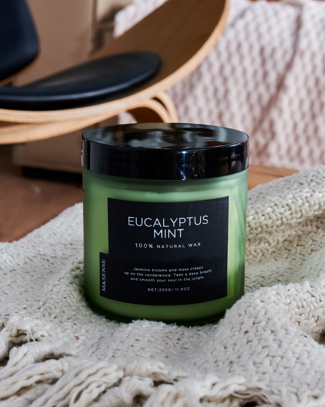 Eucalyptus mint scented candle in a green frosted jar, adding a fresh aroma to a cozy living room setting with a sofa.