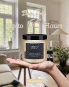 Hand holding a Vanilla Cream candle with a 65-hour burn time, showcasing its creamy scent and natural wax.