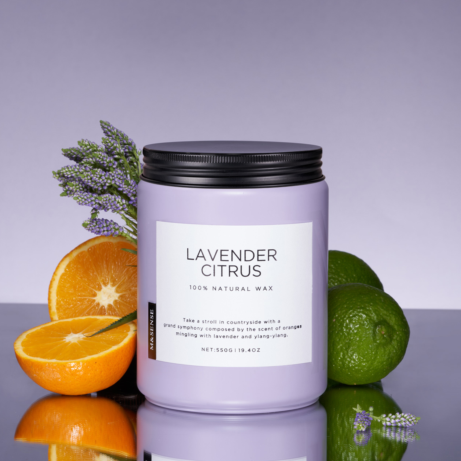 Candle labeled 'Lavender Citrus' with lavender, oranges, and limes on a reflective surface.