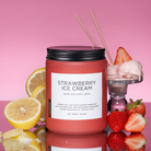 Candle labeled 'Strawberry Ice Cream' with lemons, strawberries, and a glass of ice cream on a pink background.