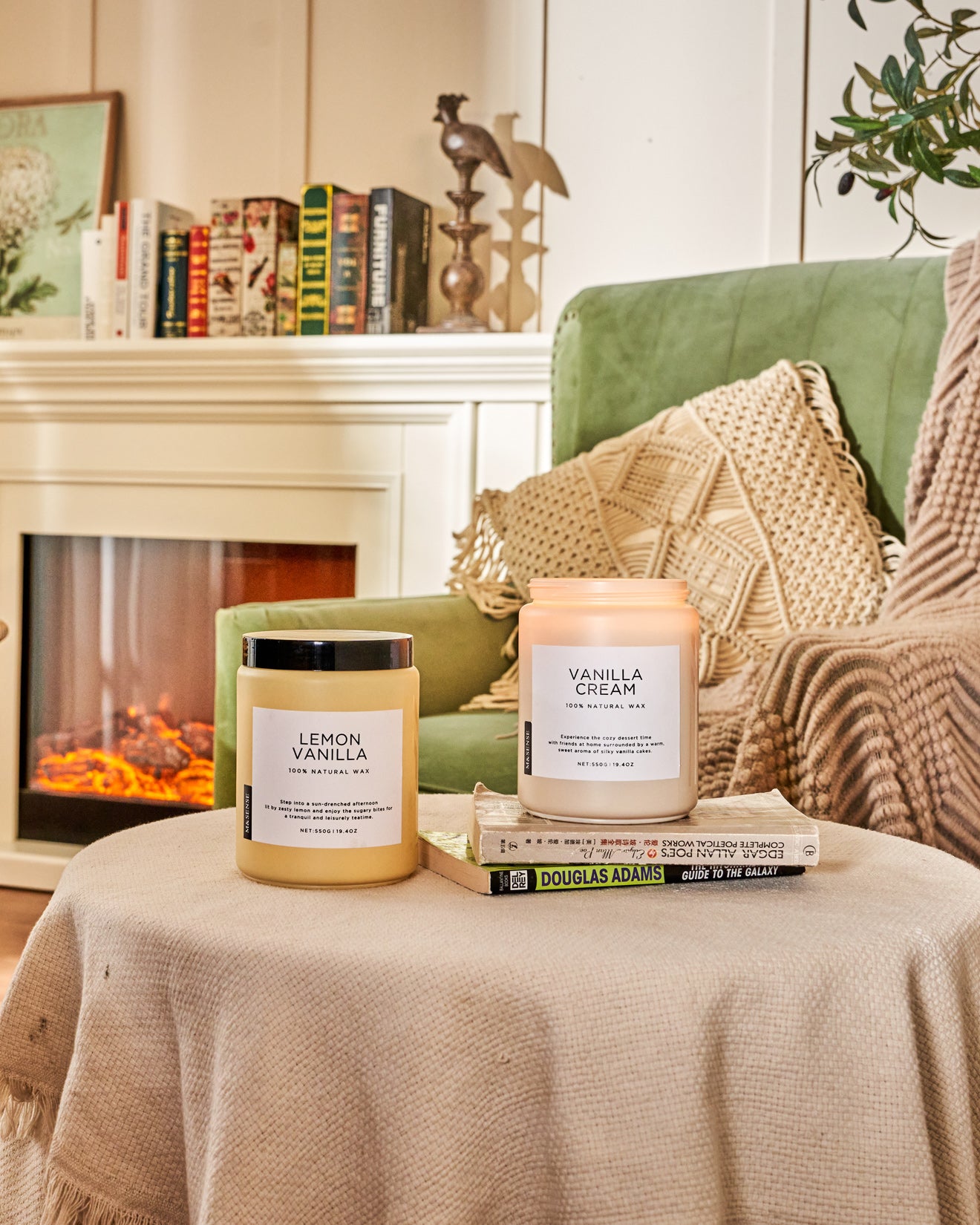 Two scented candles on a draped round coffee table, in a living room with sofa and bookshelf.