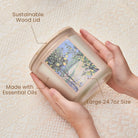 Hands holding a container with text highlighting features like 'Sustainable Wood Lid', 'Made with Essential Oils', and 'Large 24.7oz Size'.